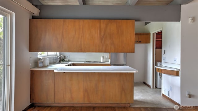 kitchen featuring plenty of natural light, brown cabinets, light countertops, and a peninsula