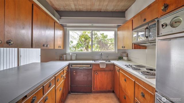 kitchen with light countertops, a sink, appliances with stainless steel finishes, and brown cabinetry