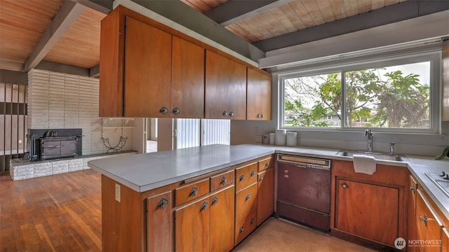 kitchen with a sink, light countertops, beam ceiling, and dishwasher