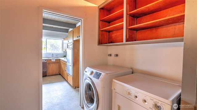 clothes washing area featuring a sink, washing machine and dryer, and laundry area