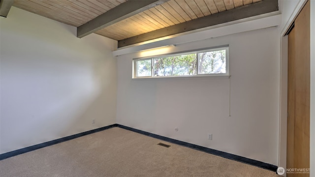 empty room with visible vents, baseboards, beam ceiling, carpet floors, and wood ceiling