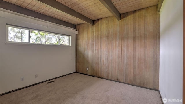 carpeted empty room featuring baseboards, beamed ceiling, visible vents, and wooden ceiling