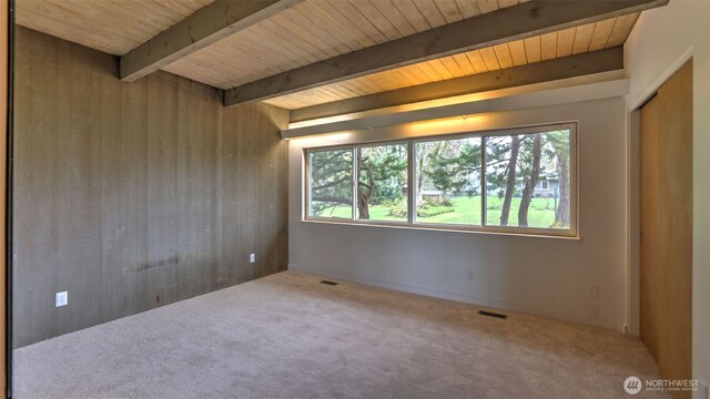carpeted spare room featuring wood ceiling, visible vents, a healthy amount of sunlight, and beamed ceiling