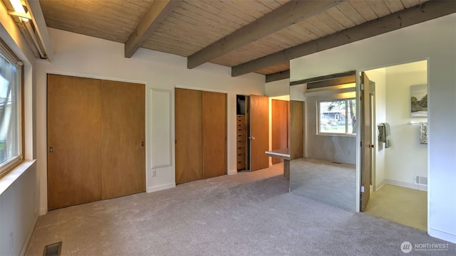 unfurnished bedroom with beam ceiling, wood ceiling, carpet flooring, visible vents, and two closets