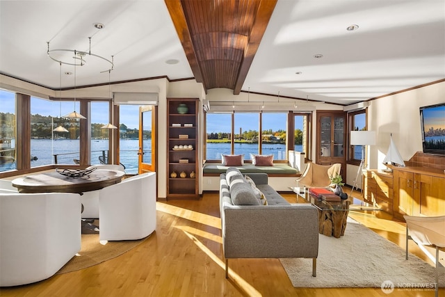 interior space with vaulted ceiling, wood finished floors, a wealth of natural light, and ornamental molding