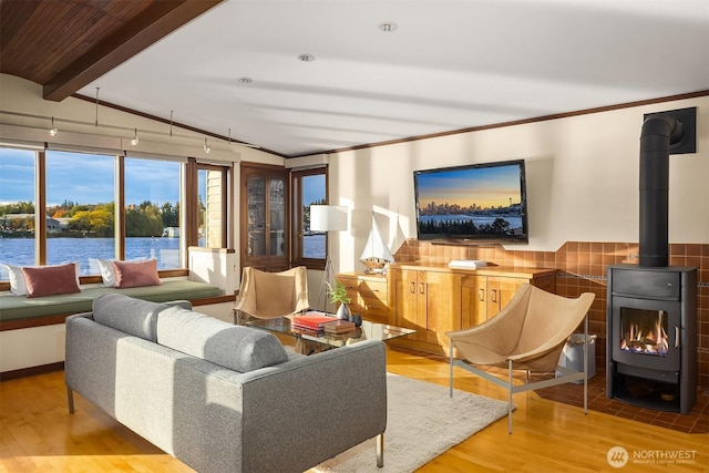 living room featuring wood finished floors, a wood stove, crown molding, and a water view