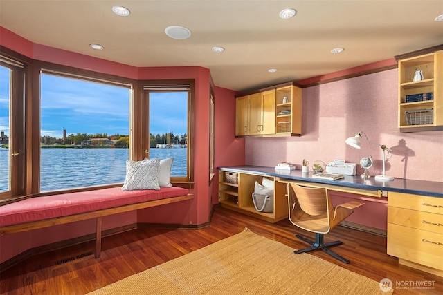 office space featuring wood finished floors, built in desk, recessed lighting, and a water view