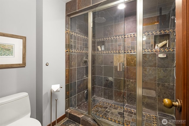 bathroom featuring a shower stall, toilet, and baseboards
