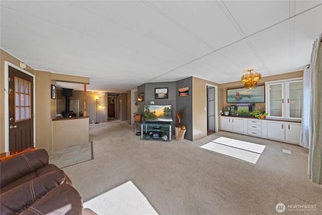 living area with carpet floors, a wood stove, and a chandelier