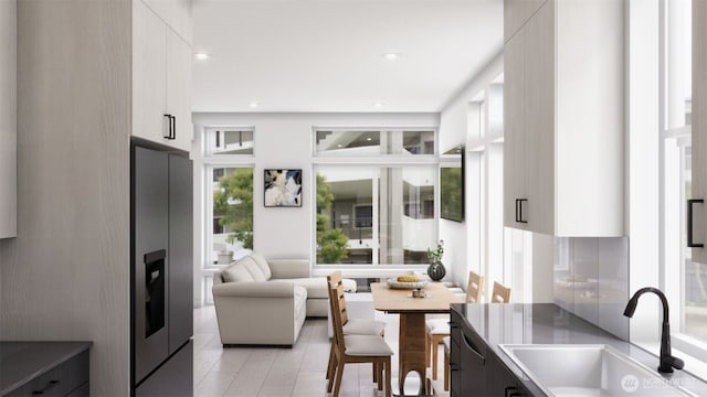 kitchen featuring white cabinets, a sink, stainless steel fridge with ice dispenser, open floor plan, and modern cabinets