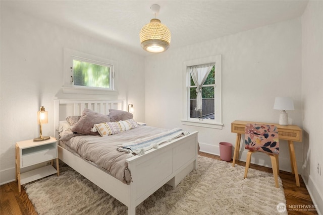 bedroom with wood finished floors, baseboards, and multiple windows