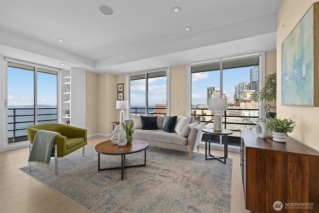 living room featuring recessed lighting, a city view, plenty of natural light, and wood finished floors