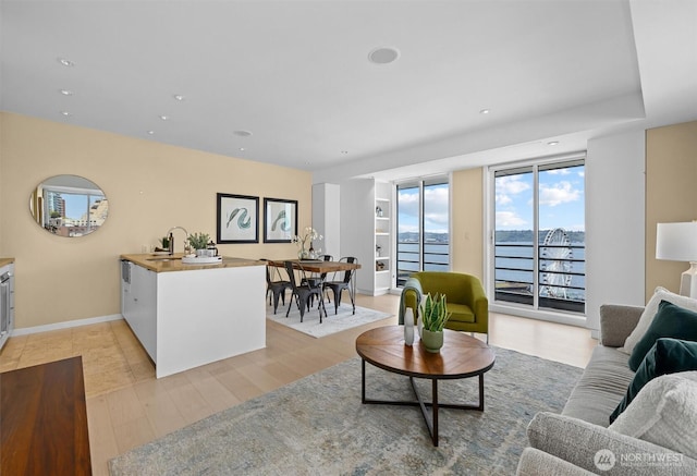 living area with baseboards, recessed lighting, and light wood-style flooring