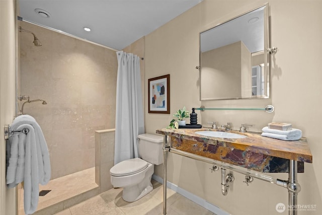 bathroom featuring tile patterned flooring, a tile shower, and toilet