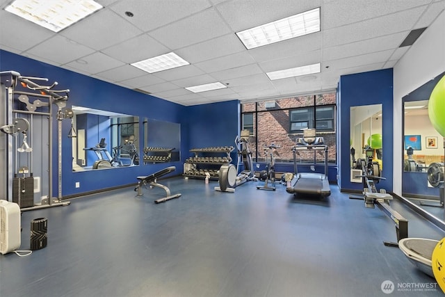 workout area featuring baseboards, floor to ceiling windows, and a paneled ceiling