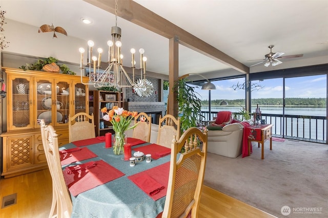 9716 Hunter Point Rd NW, Olympia, WA 98502 - dining room featuring ceiling fan, beamed ceiling, a water view, a fireplace, and a chandelier