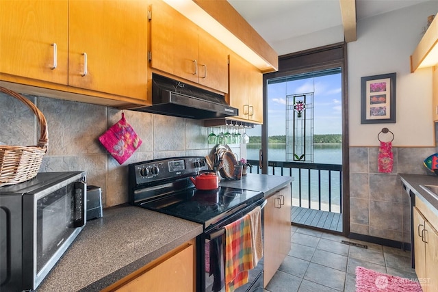 9716 Hunter Point Rd NW, Olympia, WA 98502 - kitchen with black / electric stove, under cabinet range hood, stainless steel microwave, light tile patterned floors, and tile walls