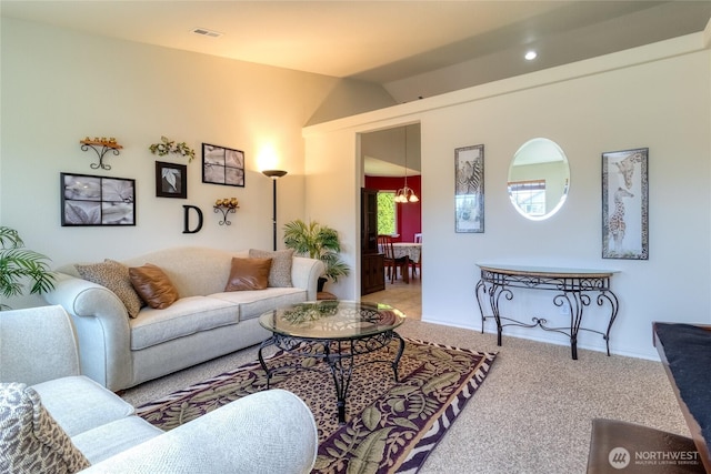 carpeted living area featuring visible vents, baseboards, and lofted ceiling