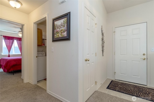 hallway with visible vents, baseboards, washer / clothes dryer, and light carpet