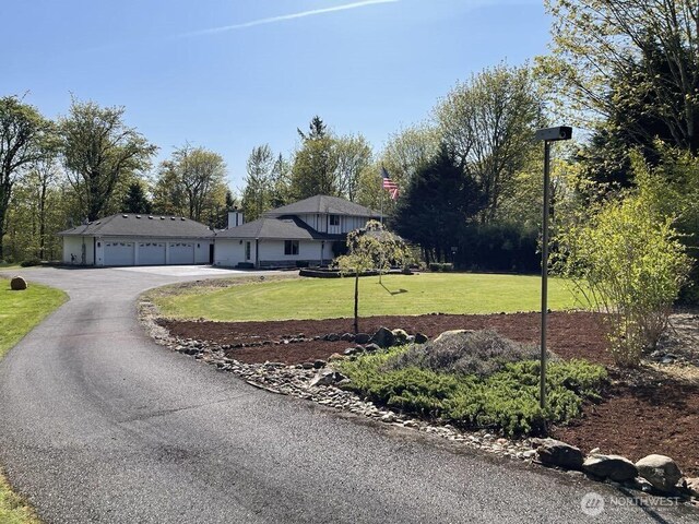 view of front of home with aphalt driveway, a front yard, and a garage
