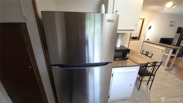 116 Galleon Loop NE, Ocean Shores, WA 98569 - kitchen with freestanding refrigerator, black microwave, white cabinetry, light tile patterned floors, and dark countertops