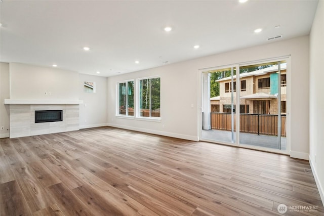 6406 213th Avenue Ct E, Bonney Lake, WA 98391 - unfurnished living room featuring wood finished floors, a tiled fireplace, and recessed lighting