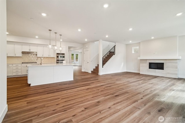 6406 213th Avenue Ct E, Bonney Lake, WA 98391 - unfurnished living room with a fireplace, light wood-style flooring, stairway, and recessed lighting