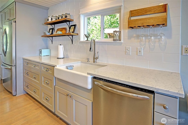 987 Cavalero Rd, Camano Island, WA 98282 - kitchen featuring light wood-style flooring, a sink, appliances with stainless steel finishes, light stone countertops, and backsplash