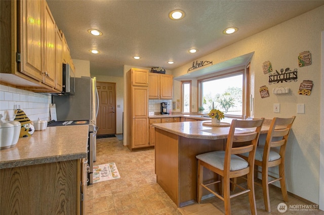 192 Canal Dr NE, Ocean Shores, WA 98569 - kitchen with a peninsula, a breakfast bar, backsplash, recessed lighting, and stainless steel electric stove