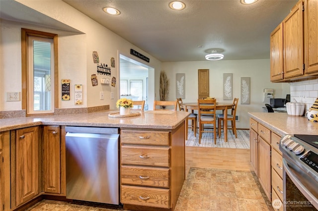 192 Canal Dr NE, Ocean Shores, WA 98569 - kitchen with stainless steel appliances, a peninsula, recessed lighting, and brown cabinetry