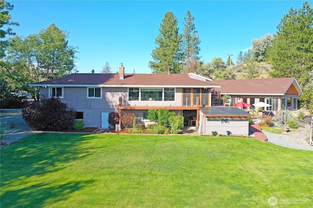 back of property with a chimney, a sunroom, and a lawn