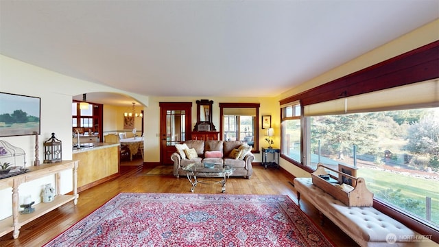 living area featuring light wood-style flooring, arched walkways, and an inviting chandelier