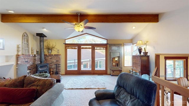 carpeted living room featuring lofted ceiling with beams, ceiling fan, a wood stove, and plenty of natural light