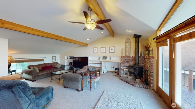 carpeted living area featuring vaulted ceiling with beams, a wood stove, and ceiling fan