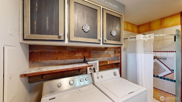 clothes washing area featuring washing machine and clothes dryer and cabinet space
