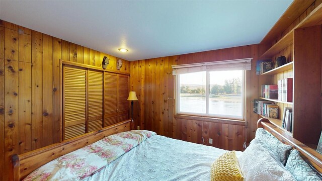 bedroom featuring a water view, a closet, and wooden walls