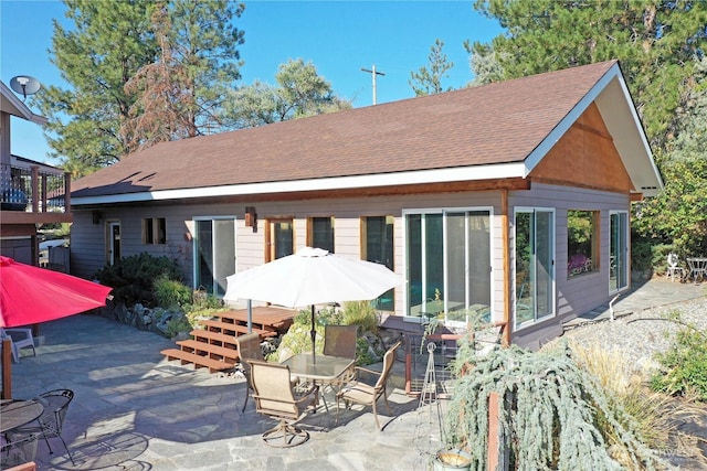 rear view of property with a shingled roof and a patio area