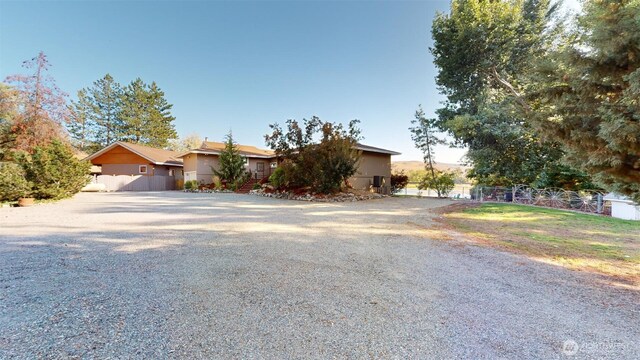 view of front facade featuring gravel driveway, fence, and stucco siding