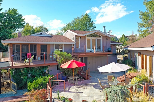 rear view of house featuring a chimney, outdoor dining area, a deck, roof with shingles, and a patio area