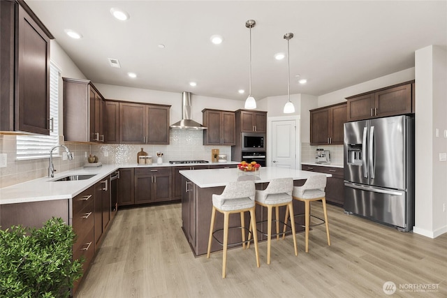 16226 SE 133rd Pl Unit 104, Renton, WA 98059 - kitchen with appliances with stainless steel finishes, wall chimney exhaust hood, a sink, a center island, and light wood-style flooring
