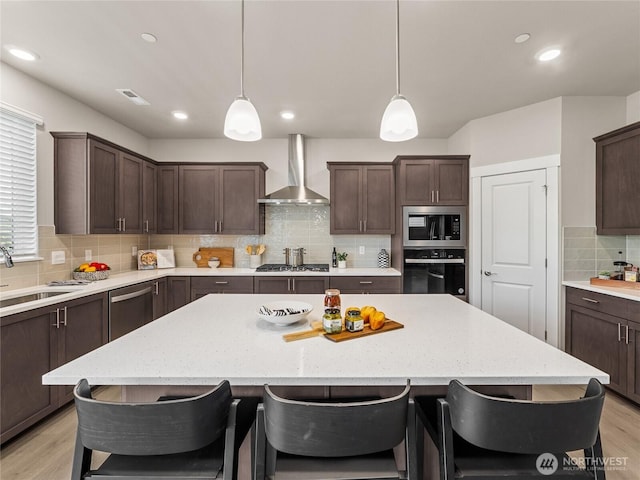 16226 SE 133rd Pl Unit 104, Renton, WA 98059 - kitchen featuring wall chimney exhaust hood, stainless steel appliances, backsplash, dark brown cabinetry, and recessed lighting
