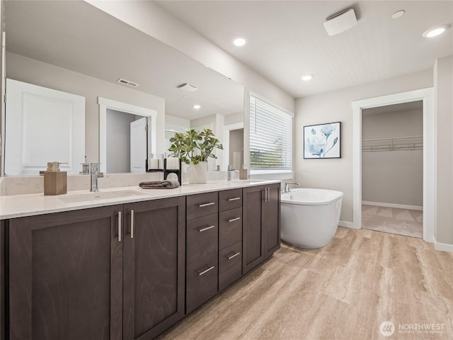 16226 SE 133rd Pl Unit 104, Renton, WA 98059 - bathroom featuring double vanity, a freestanding bath, wood finished floors, a spacious closet, and baseboards