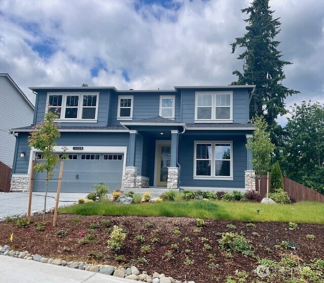 16226 SE 133rd Pl Unit 104, Renton, WA 98059 - view of front of home featuring an attached garage, a porch, stone siding, and driveway