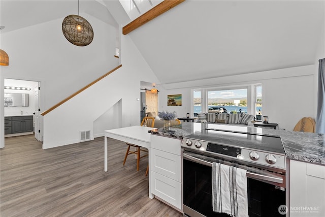 117 Water St, Chelan, WA 98816 - kitchen featuring high vaulted ceiling, stainless steel range with electric cooktop, white cabinets, visible vents, and stone countertops