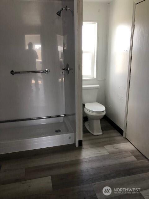 full bath featuring wood finished floors, toilet, and a shower stall
