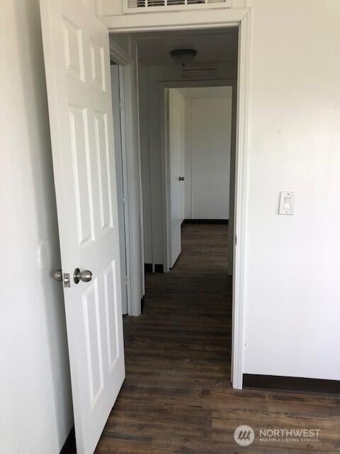 hallway featuring dark wood-style floors and visible vents