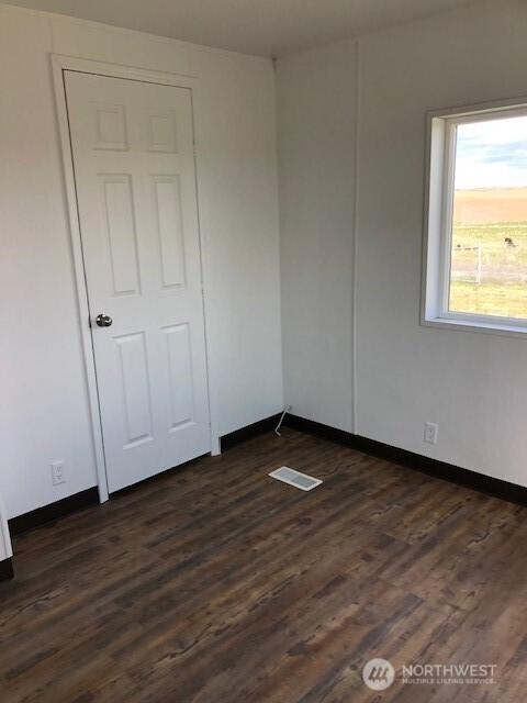 spare room with visible vents, dark wood-style flooring, and baseboards