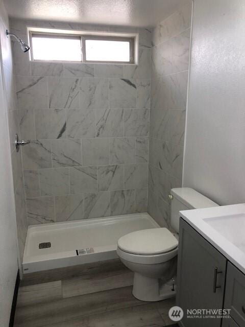 bathroom featuring vanity, a shower stall, toilet, and wood finished floors
