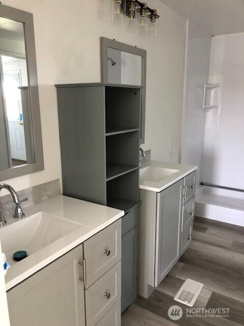 full bath with visible vents, a sink, and two vanities