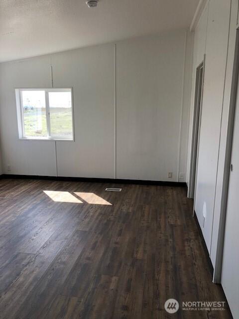 empty room with dark wood-style floors and visible vents